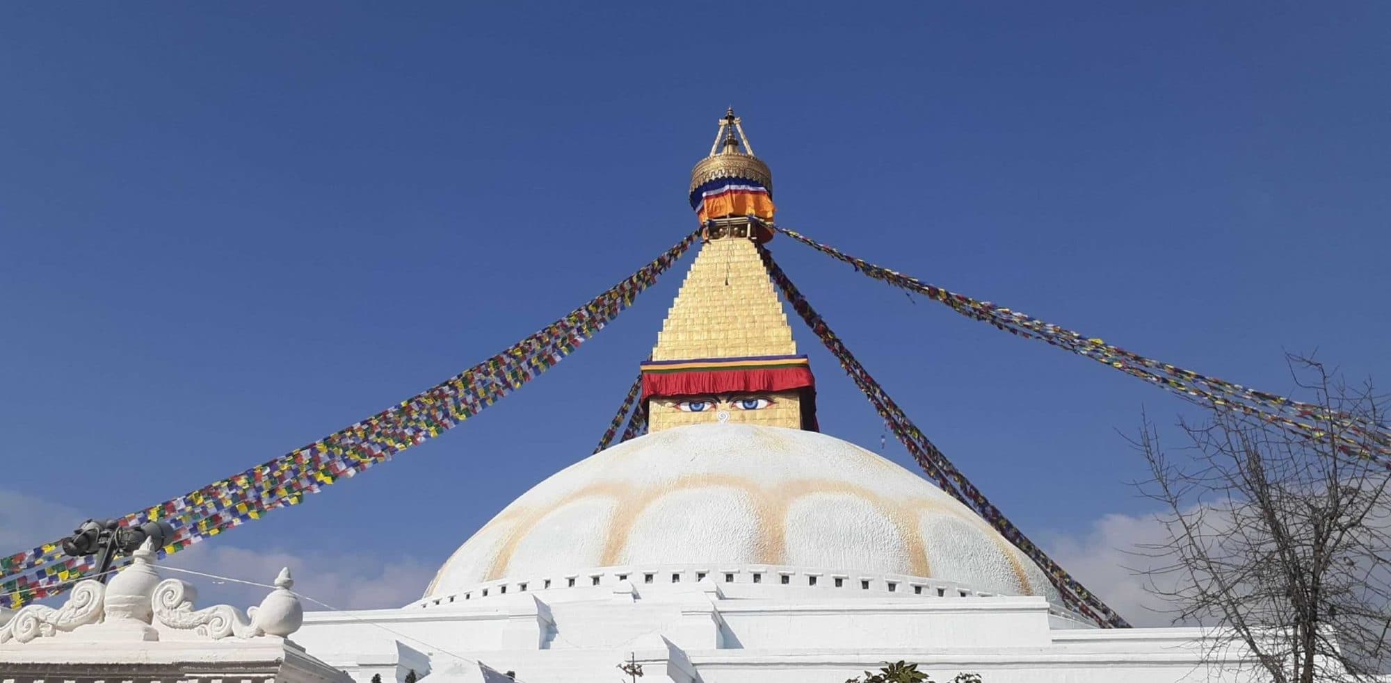 A white stupa with a golden spire and colorful prayer flags